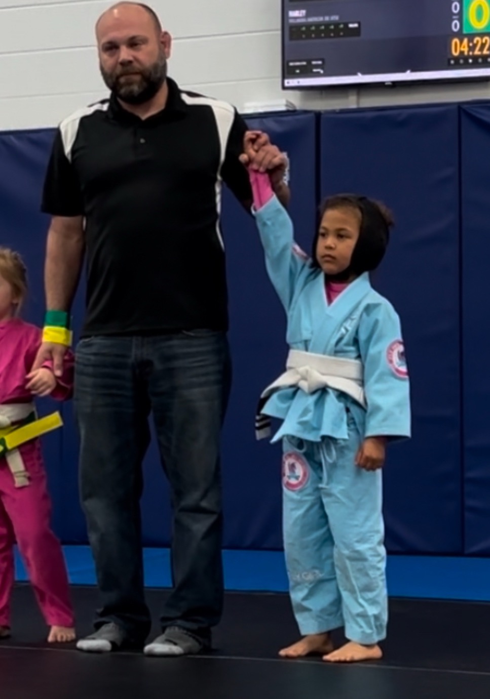 Young Xora in her light blue gi having her hand raised after a competition